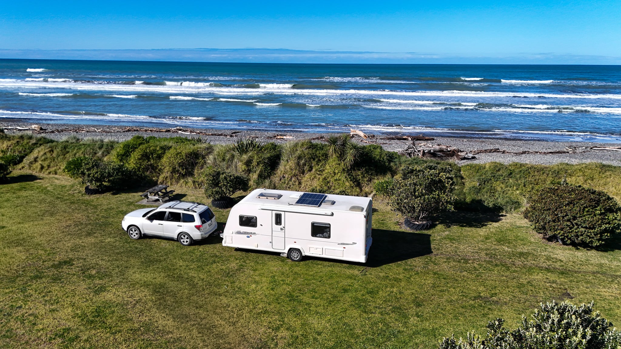 Caravan and car parked on the grass above a beach on the Canterbury coast